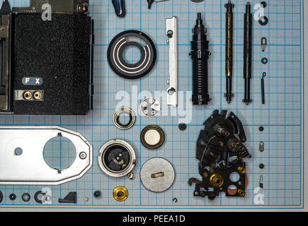 parts are completely disassembled old retro film SLR camera on graph paper, close-up Stock Photo