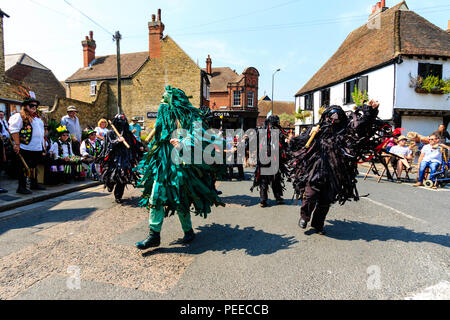 Traditional English folk dancers, the Wild Hunt Morris dance side, in black tatter jackets, dancing in the street at Sandwich Folk and Ale Festival. Stock Photo