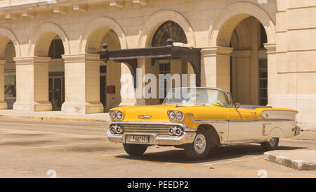 Yellow Chevrolet Impala Convertible American classic car in front of historic facade in Havana, Cuba Stock Photo