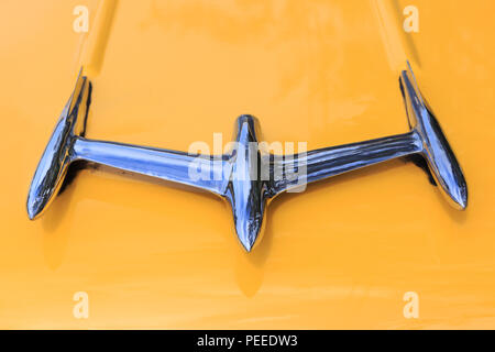 Close up of chrome hood ornament, jet ornament on Oldsmobile Holiday Starfire, yellow paint, American classic car Stock Photo