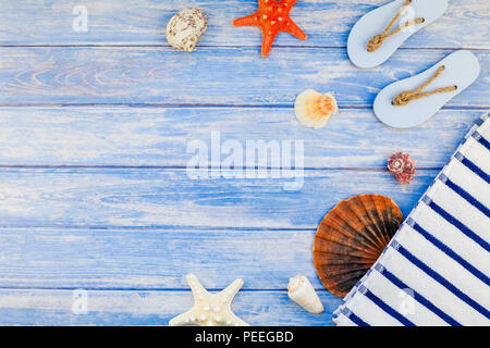 Creative flat lay concept of summer travel vacations. Top view of towel flip flops seashells and starfish on pastel blue wooden planks background with Stock Photo
