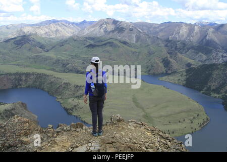 Woman stands atop the nose of the Sleeping Giant, looking at the Ming Bar of Holter Reservoir, near Helena, MT, USA Stock Photo