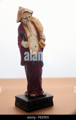 Small figurine of asian peasant man with a paddy hat, a bag on his shoulder and a walking stick Stock Photo