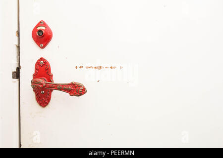 Ancient red door handle on a white broken old door close-up vintage design Stock Photo