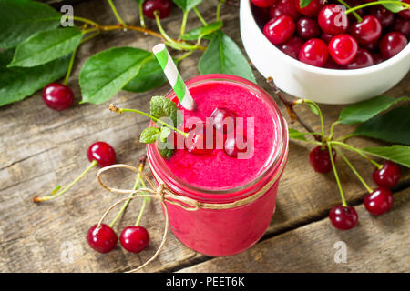 Cherry milkshake or smoothie on a dark wooden table. Healthy juicy vitamin drink diet or vegan food concept. Stock Photo