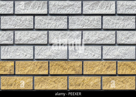 Fragment of the wall, laid out gray and yellow brick, for use as a seamless background. Stock Photo