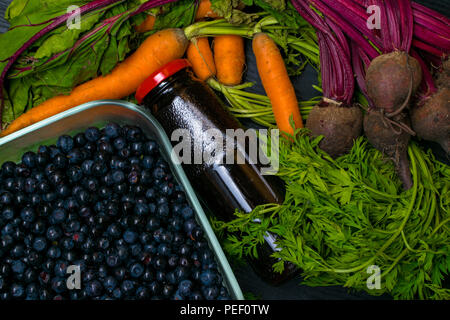 vitamin A in vegetable food, carrot, beet, pomegranate juice, blueberry in wooden background. Detox Stock Photo