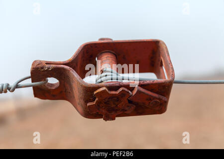 Old wire tensioner of a wire fence in a field closeup Stock Photo