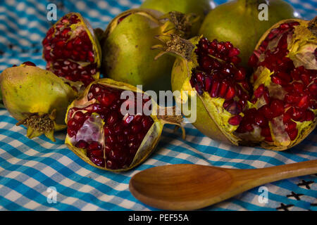close up pomegranate fruit on a blue fabric with square pattern, wood spoon Stock Photo