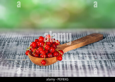 Ripe red currant berries in wooden spoon on wooden background. Copy space Stock Photo