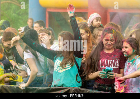 DZERZHINSK, RUSSIA - MAY 19, 2018: Happy young girl taking selfie in clouds of colored powder at the festival of Holi colors and music. Stock Photo
