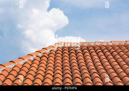 Orange roof tile pattern over blue and cloudy sky. Roof on modern house building. Close up Stock Photo