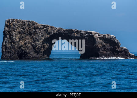 Arch Rock on the eastern tip of Anacapa Island with small waves crashing against the base on a typical blue sky day. Stock Photo