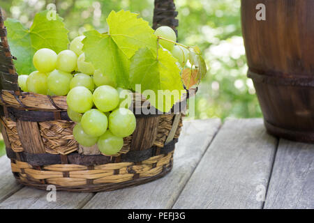 Rustic basket of fresh green grapes on an outdoors weathered wooden surface Stock Photo