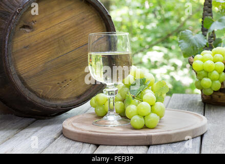 Glass of wine and green grapes on a wooden platter in a rustic oudoor setting Stock Photo