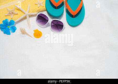 Beach accessories including sunglasses, starfish, colorful flip flop and shell on White sandy beach background background for summer holiday and vacat Stock Photo