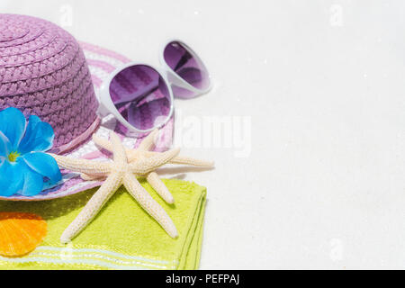 Beach accessories including sunglasses, starfish, beach hat and sea shell on White sandy beach background background for summer holiday and vacation c Stock Photo