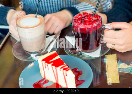 Female hands with hot drinks and sweet dessert on the table in a cafe Stock Photo
