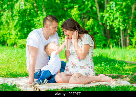 happy family on the blanket resting in the park, pregnant mother Stock Photo
