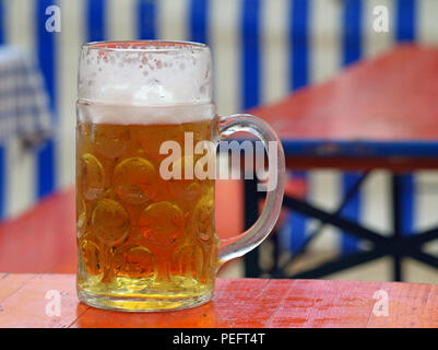 close up of bavarian beer on wooden table in front of natural blue white bavarian background Stock Photo