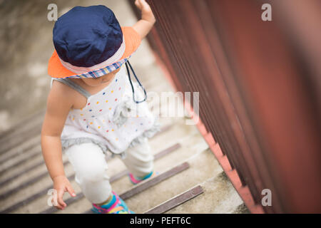 Happy little cute girl walking up the stairs. Kid first step concept. Stock Photo
