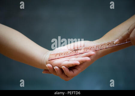 Student being physically punished by teacher with a ruler on on wooden blackboard or chalkboard background. Stock Photo