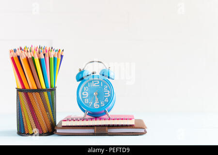 Education or back to school Concept. school office supplies. alarm clock, pencils, note books on white wooden background. Stock Photo