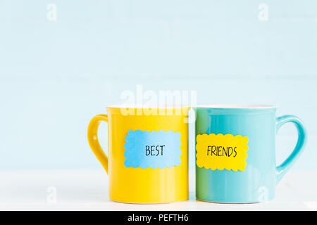 Coffee cups on wooden table with paper tag and best friends text. Friendship day celebration background Stock Photo