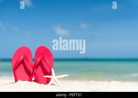happy beautiful young woman in pink bikini with flip flop on sandy beach, green sea and blue sky background for summer holiday and vacation concept. Stock Photo