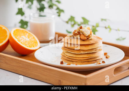 Stack of delicious pancakes with chocolate, honey, nuts and slices of banana on plate on stone background Stock Photo