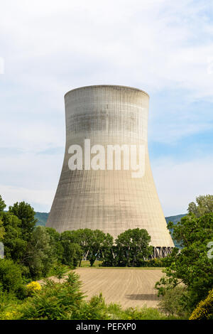 A natural draft cooling tower of a nuclear power plant releasing clouds of water vapor in the middle of the countryside with a plowed field in the for Stock Photo