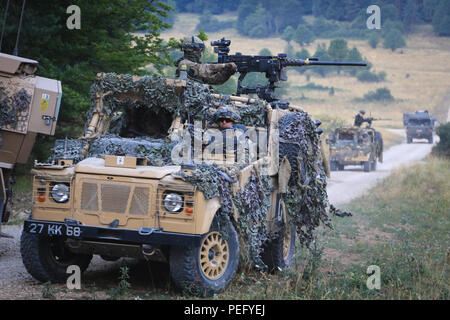 British soldiers use an armored Land Rover to secure a road checking ...