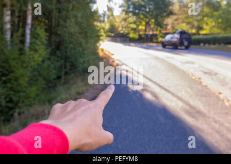 Person's hand and index finger pointing straight ahead on a street, giving directions Stock Photo