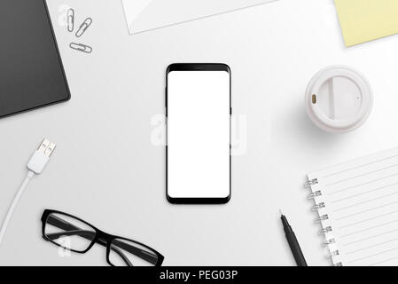 Phone with round edges on white desk. Isolated screen for app or web site presentation mockup. Flat lay. Top view. Stock Photo