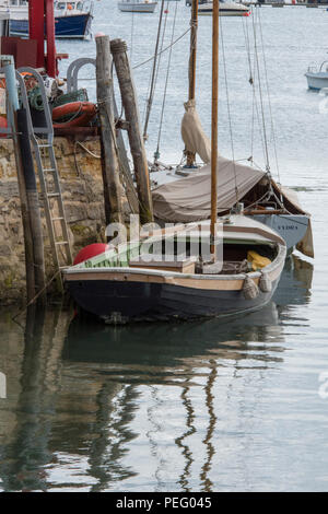 an old or traditional sailing dinghy alongside a wall in the harbour at bembridge on the isle of wight Stock Photo