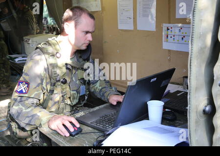 A Czech soldier assigned to Headquarters, 132nd Field Artillery Battalion, 13th Artillery Brigade, works on a computer while conducting a base defense operation during exercise Allied Spirit II at the U.S. Army's Joint Multinational Readiness Center in Hohenfels, Germany, Aug. 14, 2015. Allied Spirit II is a multinational decisive action training environment exercise that involves over 3,500 Soldiers from both the U.S., allied, and partner nations focused on building partnerships and interoperability between all participating nations and emphasizing mission command, intelligence, sustainment,  Stock Photo