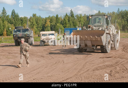 Pfc. Paola Mata, of Dallas, a heavy equipment operator with 500th Engineer Company, 15th Engineer Battalion, 18th Military Police Brigade based out of Grafenwoehr, Germany, ground guides Enlisted Jonas Sundberg, of Moss, Norway, an engineer with the Theater Enabling Force of the Norwegian Army High Readiness Force to a gravel mound near a road construction Aug. 19, at the Central Training Area near Tapa, Estonia. The efforts are a part of Operation Atlantic Resolve, an ongoing series of training operations and events designed to build relationships, trust and interoperability between the U.S.  Stock Photo