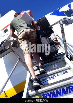 Rear view of Male Passenger climbs up the plane steps to board a Ryanair flight Stock Photo