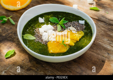 Green smoothie bowl with banana, spinach, chia seeds and oranges Stock Photo