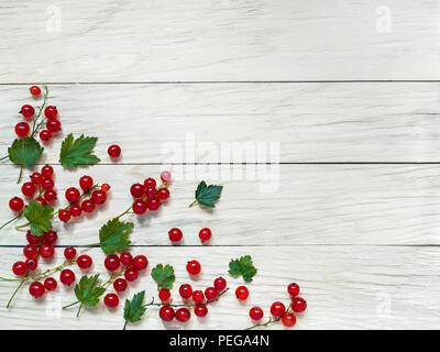 Fresh large red currant berries with green leaves lie on a plank background removed from above close-up Stock Photo