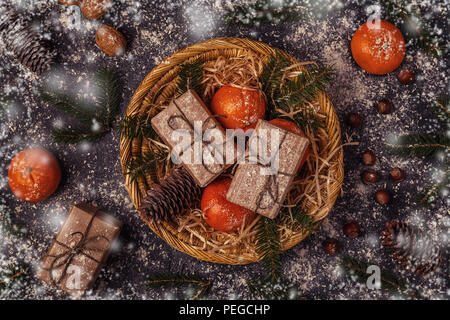 Christmas composition with tangerines, gift boxes, cones on dark  background. Stock Photo
