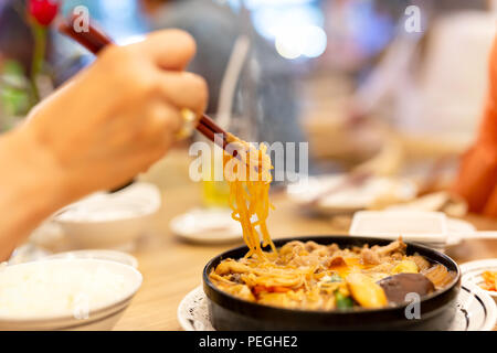 Hand with chopsticks eating Japanese udon noodles. Stock Photo