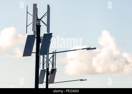 Wind turbine with solar panels on pillar against sky background. Public city light with solar panel powered on blue sky with clouds Stock Photo