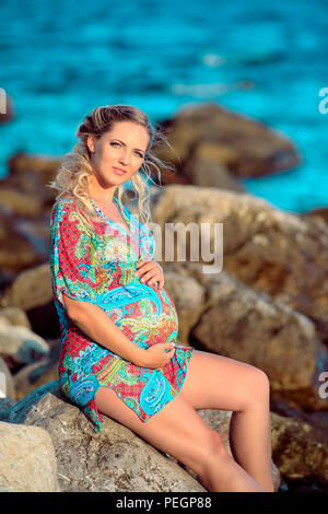 pregnancy women siting on the rock on sunset light Stock Photo