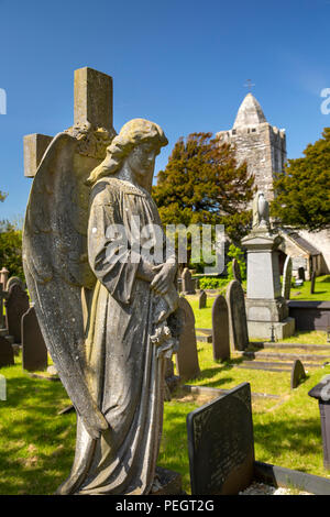 UK, Wales, Anglesey, Llanfechell, angel memorial in St Mechell’s churchyard with unusual spire to tower Stock Photo