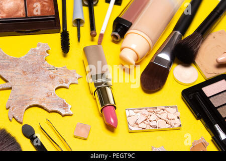 Autumn makeup. Make up products brown and golden colors on yellow background Stock Photo