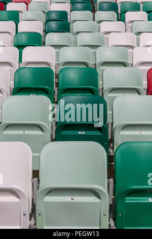 Rows of empty chairs on tribunes of a modern stadium without spectators and colored chairs with numbers in the center of the arena Stock Photo