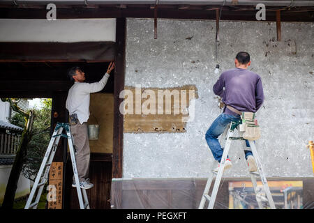 Two Japanese men restoring an old building in Kyoto, Japan. Stock Photo