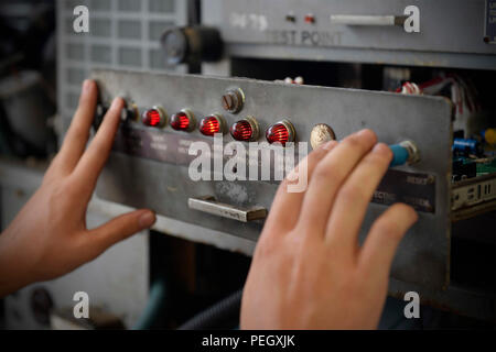 An aerospace ground equipment journeyman with the 36th Maintenance Squadron at Andersen Air Force Base, Guam, checks indicator lights on a power generator control console on Aug. 12, 2015. The maintainers are responsible for inspecting, testing, and maintaining ground support equipment critical for aircraft preflight operations. Tasks include monitoring system indicators, verifying functionality, performing preventive maintenance, and ensuring operational readiness, reliability, and safety of mechanical and electrical systems supporting flight operations. Stock Photo