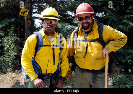 Second Lt. Julian Crockett, left, crew six leader, strike team two, Task Force First Round out of Joint Base Lewis-McChord, Wash., and Chris Scott, a military crew adviser tasked to provide oversight of Soldiers of Task Force First Round, pose for a photo in between conducting fire suppression techniques in the hope of slowing down the wildfire burning through Colville National Forest, Wash., Aug. 25, 2015. “We are both reserved but we both know how it use our chain of commands,” said Scott. “Our own personalities may be reserved but with that, we can use the sergeants as needed to relay infor Stock Photo